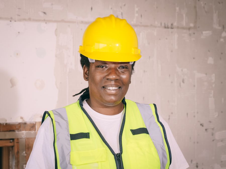 Smiling female engineer in a yellow hard hat looking at the camera